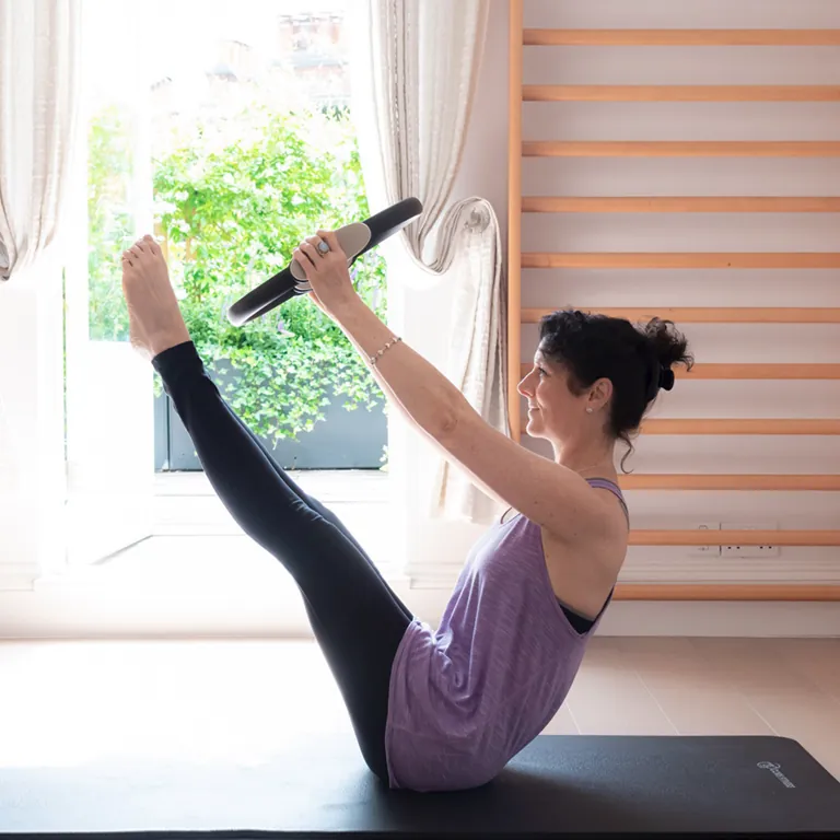 Samantha Flower balancing with a Pilates ring on a floor mat