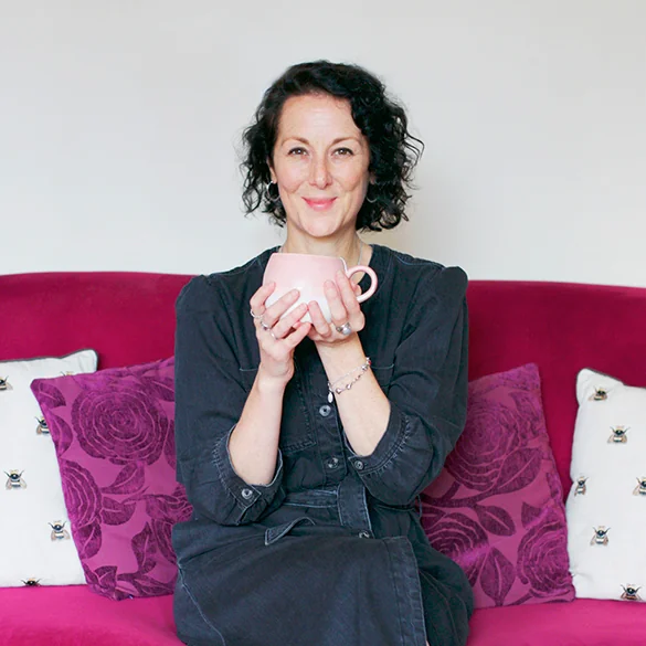 Samantha Flower sitting on a sofa, holding a cup of tea