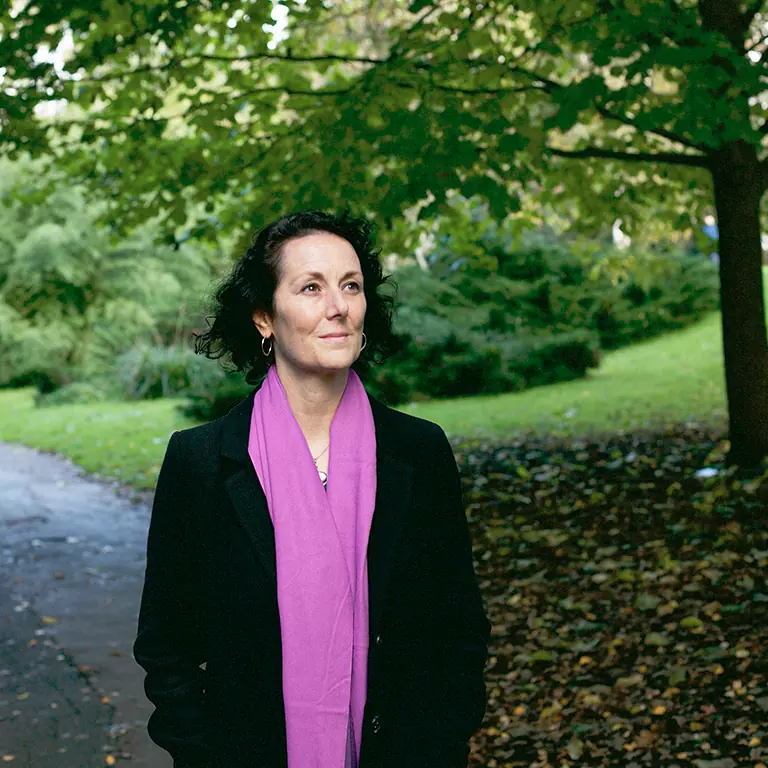 Samantha Flower walking in a park, on a path next to a tree