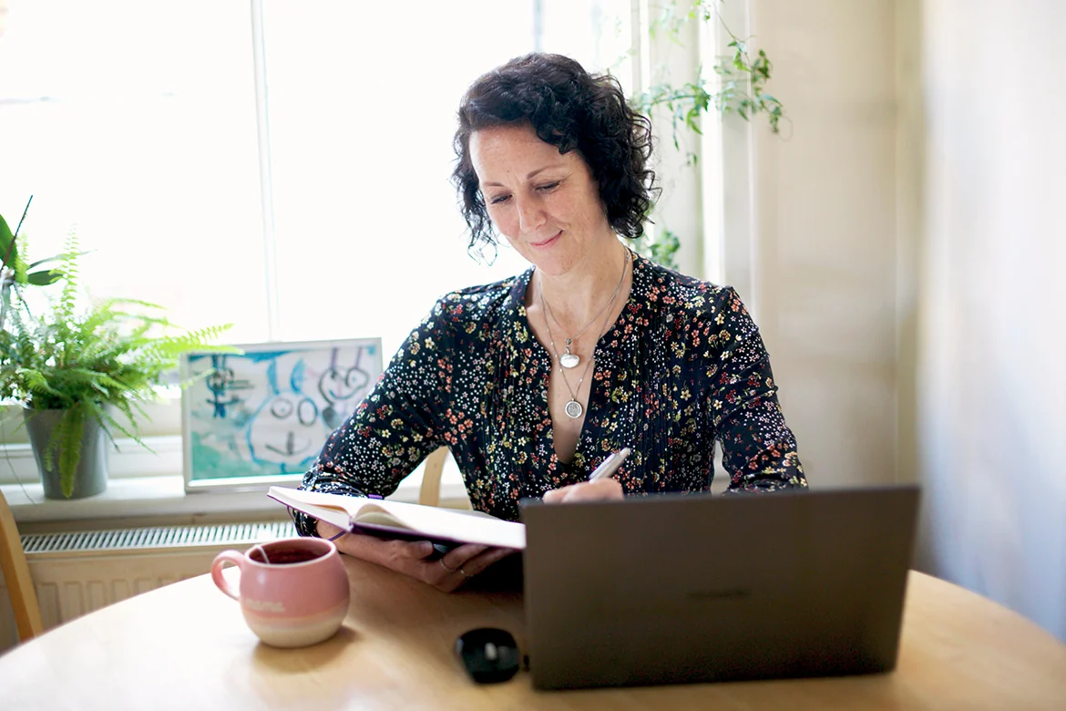 Samantha Flower sitting at a table, working with a book and a laptop