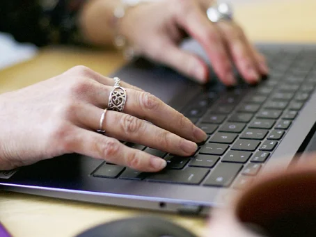 Close-up of hands typing on a laptop keyboard